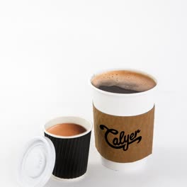 Drip coffee in a kraft-sleeved Calyer cup next to an espresso